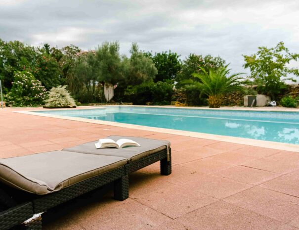 Vista de una piscina con libro en tumbona relajante