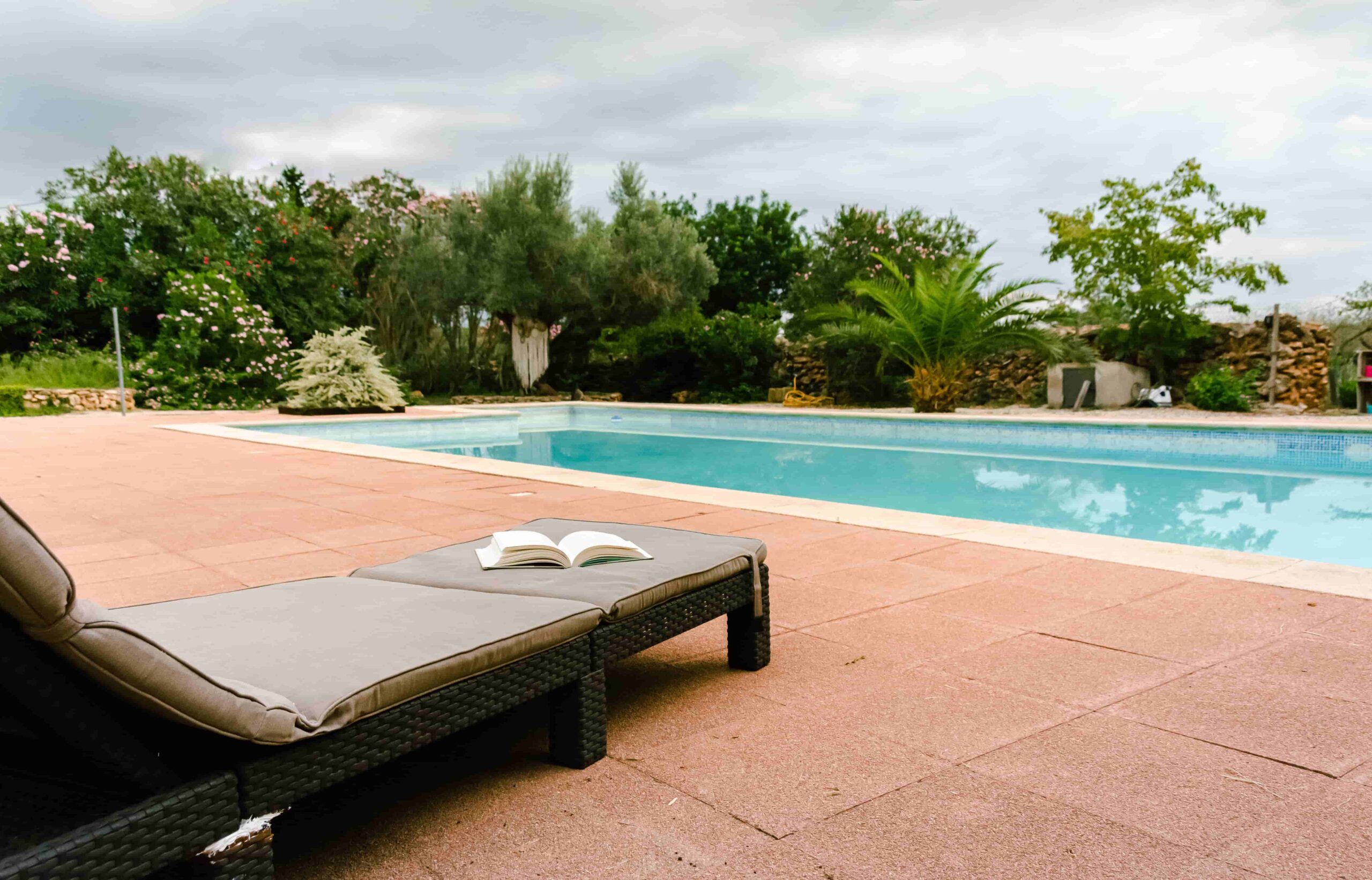 Vista de una piscina con libro en tumbona relajante